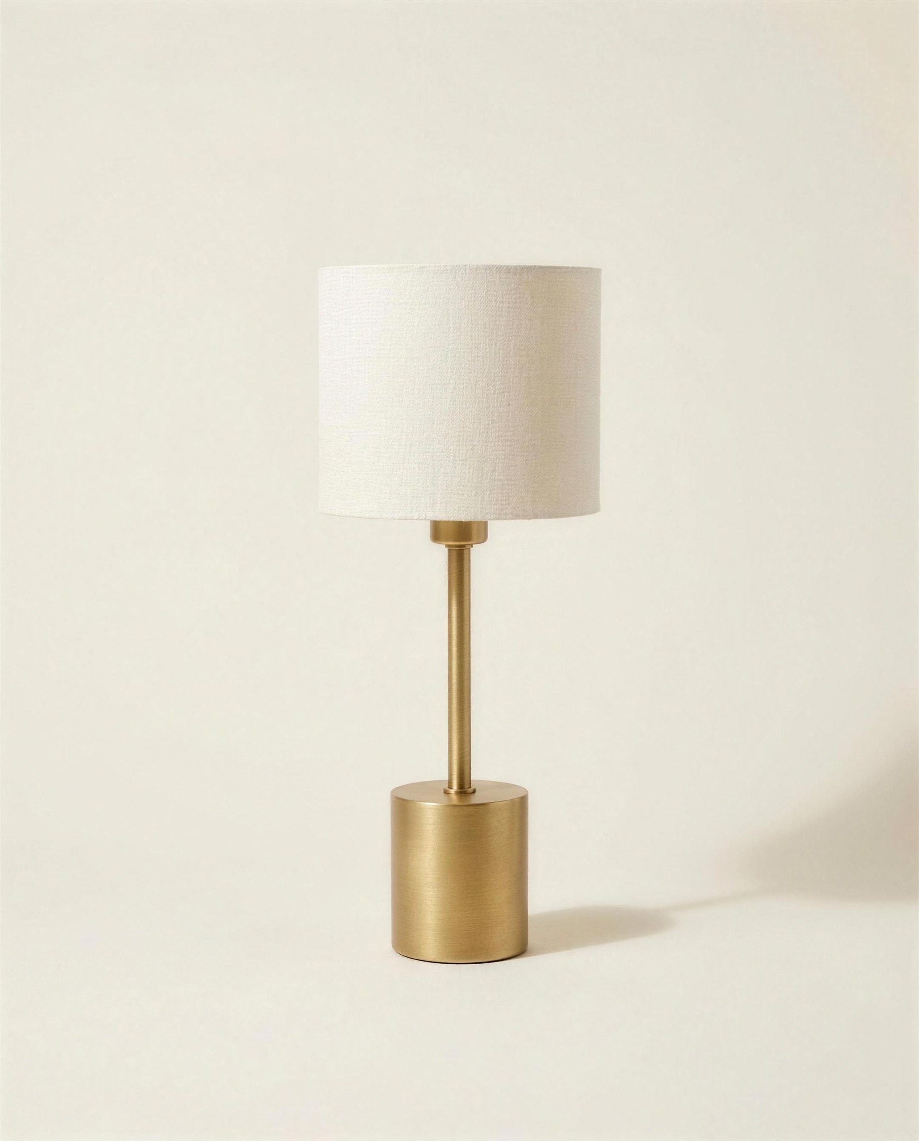 The Aalto Table Lamp: a cast brass cylindrical base and stem under a small off-white linen drum shade.
