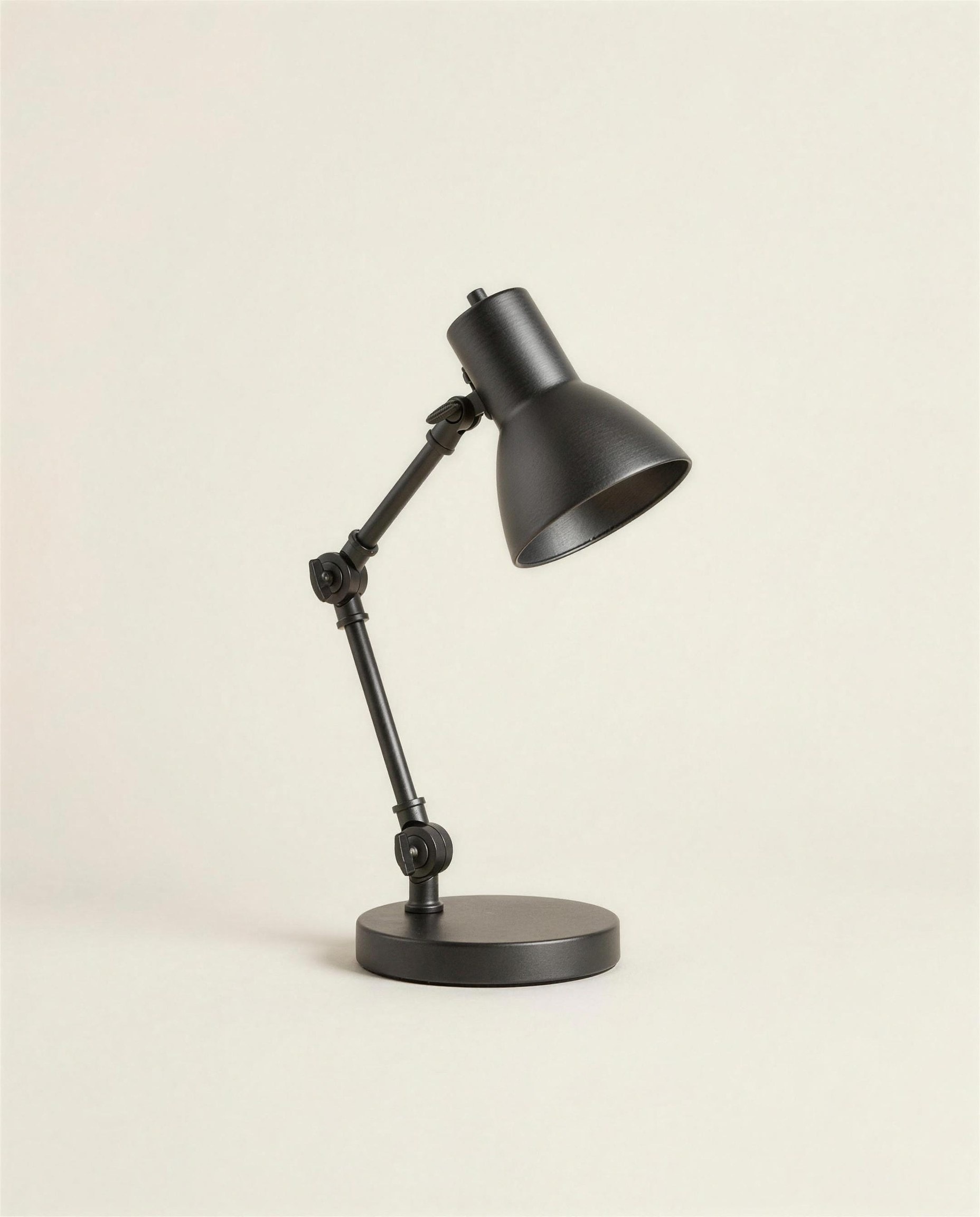 The Ansel Desk Lamp: a blackened steel task lamp with an articulated arm and conical shade on a heavy disc base.