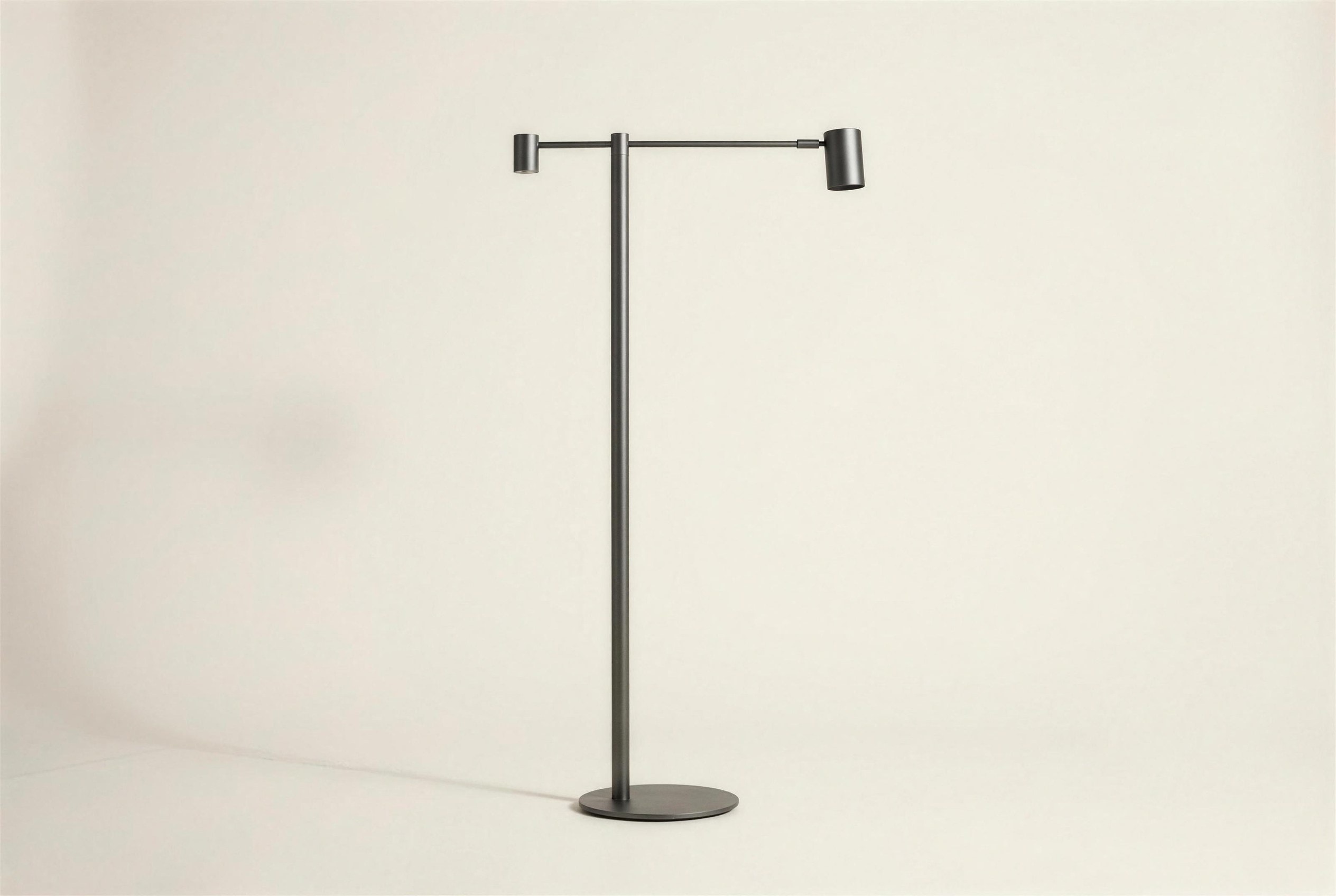 The Halden Floor Lamp: a blackened steel column on a round base, carrying a horizontal arm with two pivoting cylindrical heads.