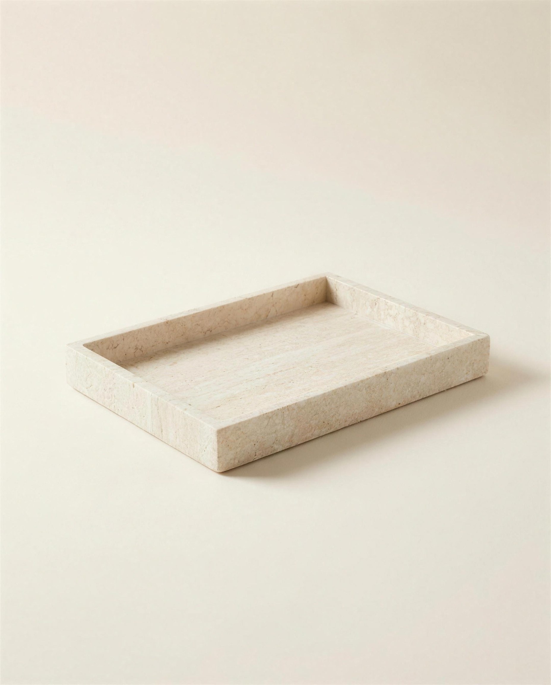 The Pell Travertine Tray: a shallow rectangular tray cut from pale cream travertine with low straight walls.